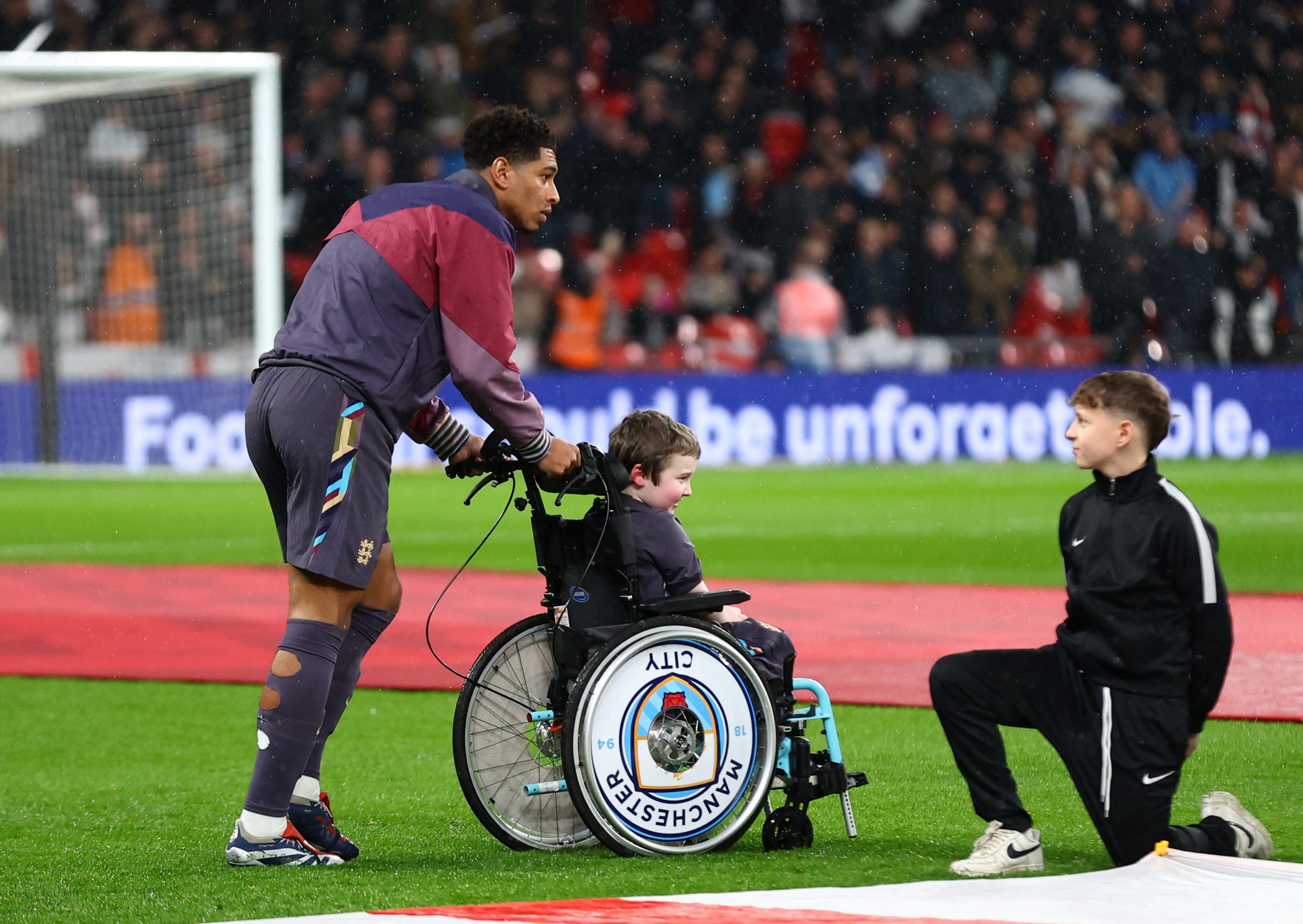 Touching moment as England star Bellingham gives his tracksuit top to mascot in wheelchair as it rains at Wembley